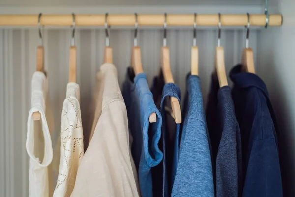 Ropa en perchas en el gradiente del gabinete de blanco a azul oscuro —  Fotos de Stock