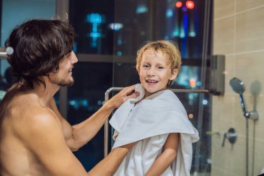 Baba oğlu bir havlu ile bir pencere arka planda şehrin panoramik manzaralı uyumaya gitmeden önce akşam duştan sonra mendil