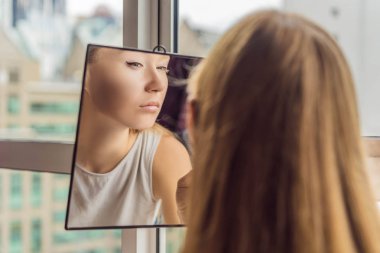 Genç kadın gökdelenler ve büyük şehrin panoramik manzaralı cam kenarında oturan makyaj yapar