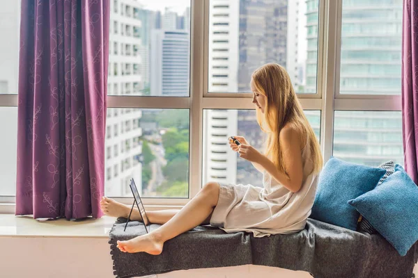 Giovane donna fa il trucco seduto vicino alla finestra con una vista panoramica dei grattacieli e la grande città — Foto Stock