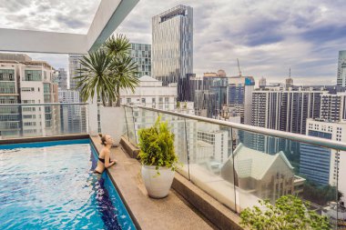 Genç kadın arasında gökdelenler ve büyük şehrin havuzunda. Büyük şehirde sakin ol. Stresten dinlenme