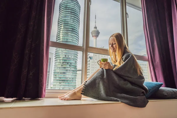 Mujer envuelta en una manta y mirando a la gran ciudad — Foto de Stock