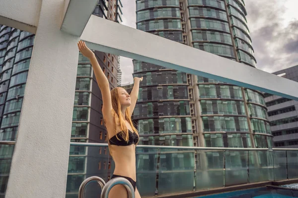 Mujer joven en la piscina entre los rascacielos y la gran ciudad. Relájate en la gran ciudad. Descanso del estrés — Foto de Stock