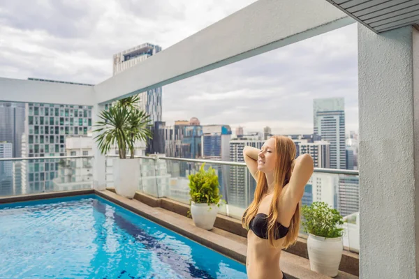 Mujer joven en la piscina entre los rascacielos y la gran ciudad. Relájate en la gran ciudad. Descanso del estrés — Foto de Stock