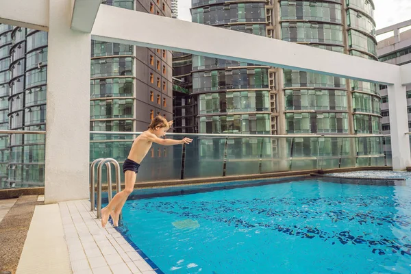 Boy jumping into the pool among the skyscrapers and the big city. Relax in the big city. Rest from stress