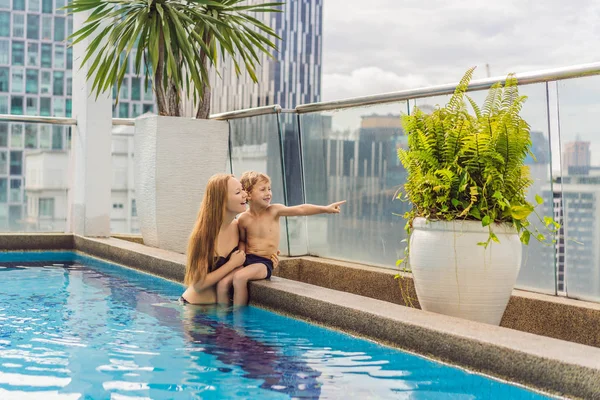 Madre e hijo en la piscina entre los rascacielos y la gran ciudad. Relájate en la gran ciudad. Descanso del estrés — Foto de Stock