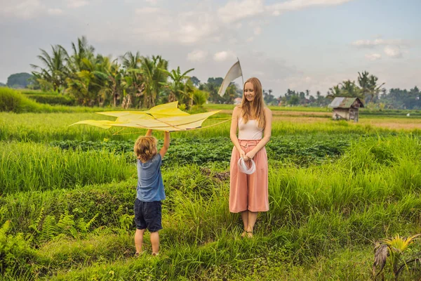 Moeder en zoon lanceren een vlieger in een veld van de rijst in Ubud, Bali eiland, Indonesië — Stockfoto