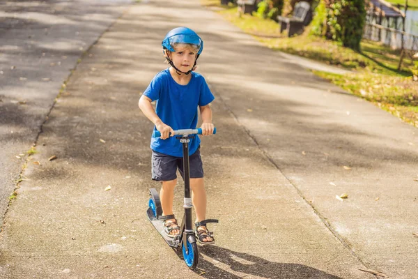 Niño montando scooters, al aire libre en el parque, verano. Los niños son felices jugando al aire libre —  Fotos de Stock