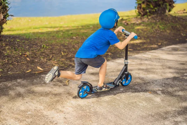 Ragazzo che guida scooter, all'aperto nel parco, d'estate. I bambini sono felici giocando all'aperto — Foto Stock