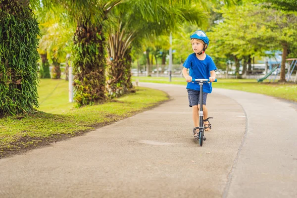 Rapaz a andar de scooters, ao ar livre no parque, no Verão. As crianças estão felizes brincando ao ar livre — Fotografia de Stock