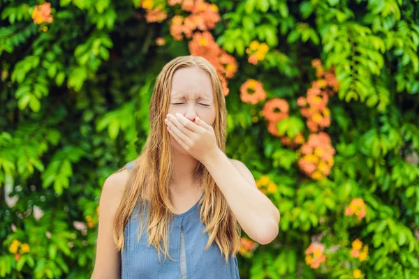 若いきれいな女性が花の木の前で鼻を吹いている。春のアレルギーコンセプト — ストック写真
