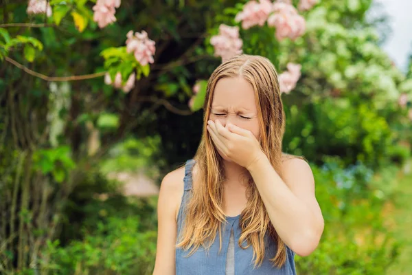 若いきれいな女性が花の木の前で鼻を吹いている。春のアレルギーコンセプト — ストック写真