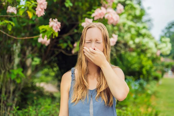 Młoda piękna kobieta dmuchająca nos przed kwitnącym drzewem. Wiosenna koncepcja alergii — Zdjęcie stockowe