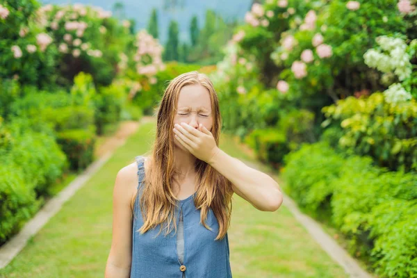 Wanita cantik muda meniup hidung di depan pohon mekar. Konsep alergi musim semi — Stok Foto