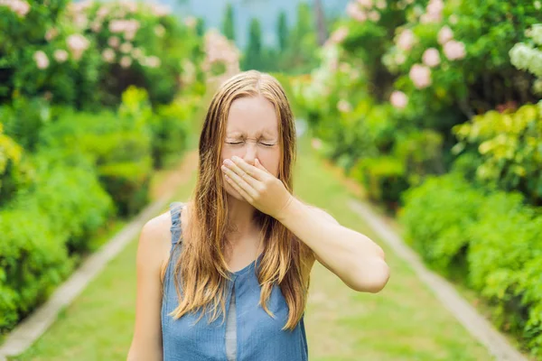 Giovane bella donna che soffia il naso davanti a un albero in fiore. Concetto allergia primaverile — Foto Stock