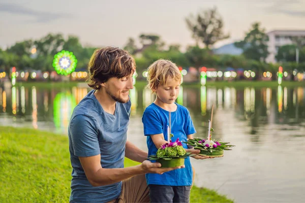 Father and son tourists celebrates Loy Krathong, Runs on the water. Loy Krathong festival, People buy flowers and candle to light and float on water to celebrate the Loy Krathong festival in Thailand