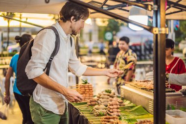 Yürüyen cadde Asya gıda pazarında genç bir turist.