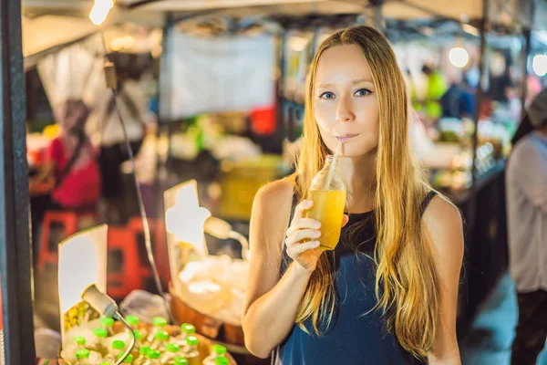 Женщина пьет сок сахарного тростника на азиатском рынке — стоковое фото
