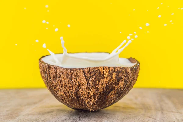 Fruits de noix de coco et éclaboussure de lait à l'intérieur sur fond jaune — Photo