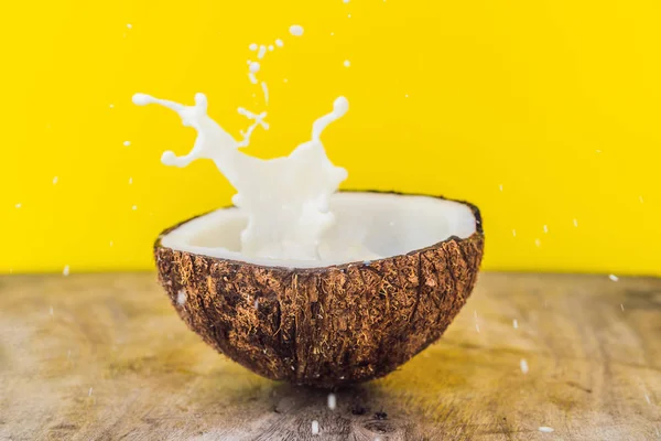 Fruits de noix de coco et éclaboussure de lait à l'intérieur sur fond jaune — Photo