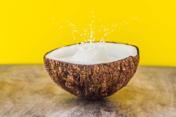 Fruta de coco e leite respingo dentro dele no fundo amarelo — Fotografia de Stock