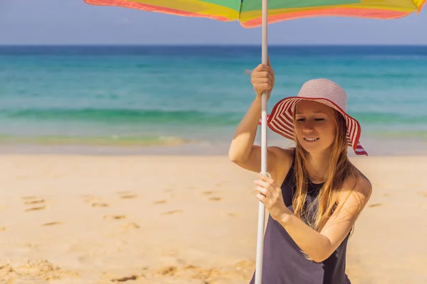 Giovane donna in spiaggia con cappello e ombrellone — Foto Stock