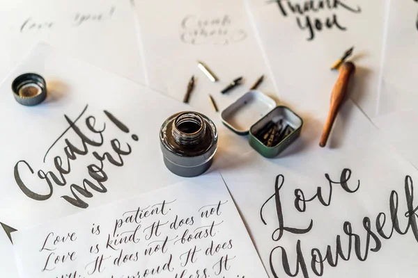 Papier, inkt, kalligrafie pennen en inscripties. Belettering workshop details. Beschilderen sier versierde letters. Kalligrafie, grafisch ontwerp, belettering, handschrift, creatie concept — Stockfoto