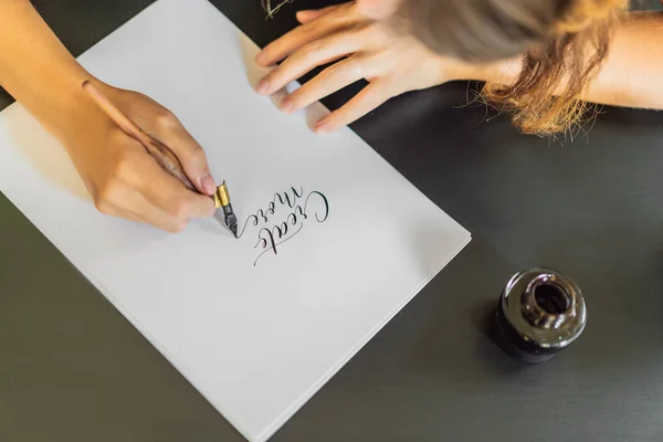 Kalligraaf handen schrijft zin op wit papier. Zin - meer maken. Beschilderen sier versierde letters. Kalligrafie, grafisch ontwerp, belettering, handschrift, creatie concept — Stockfoto