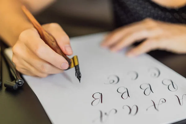 Le mani di calligrafo scrivono frasi su carta bianca. Inscrivendo lettere ornamentali decorate. Calligrafia, grafica, lettering, calligrafia, concetto di creazione — Foto Stock