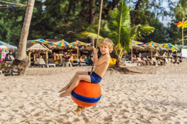 Sahilde bir salıncak üzerinde bir çocuk. Anne ve oğlu sahilde vakit