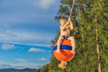 Sahilde bir salıncak üzerinde bir çocuk. Anne ve oğlu sahilde vakit