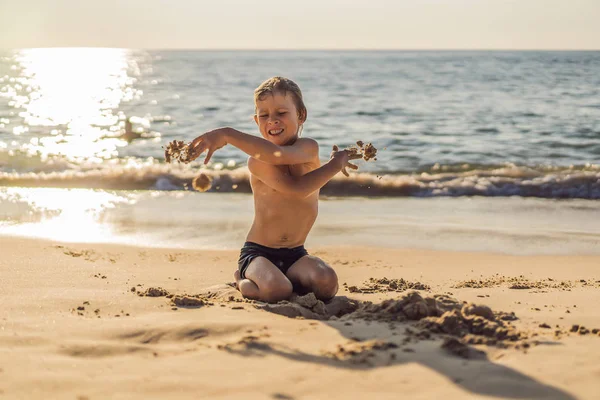 Le garçon crie et panique sur la plage, jette du sable. Concept de tantrum — Photo