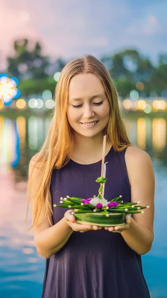 Young woman celebrates Loy Krathong, Runs on the water. Loy Krathong festival, People buy flowers and candle to light and float on water to celebrate the Loy Krathong festival in Thailand VERTICAL