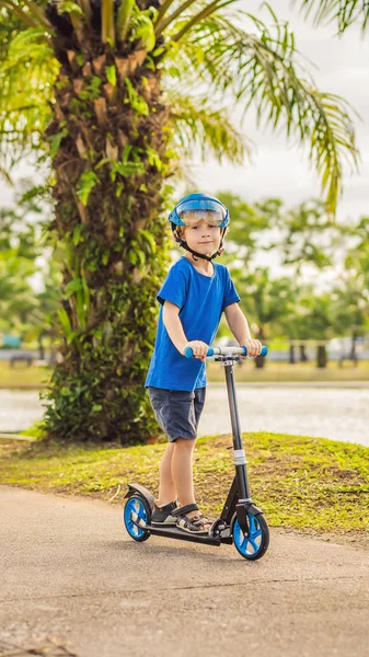 Ragazzo che guida scooter, all'aperto nel parco, d'estate. I bambini sono felici di giocare all'aperto VERTICAL FORMAT per Instagram storia mobile o dimensioni storie. Carta da parati mobile — Foto Stock