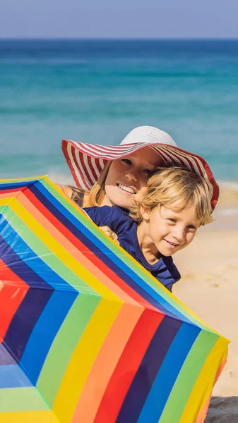 Madre e figlio in spiaggia in cappello e ombrellone FORMATO VERTICALE per Instagram storia mobile o dimensioni storie. Carta da parati mobile — Foto Stock