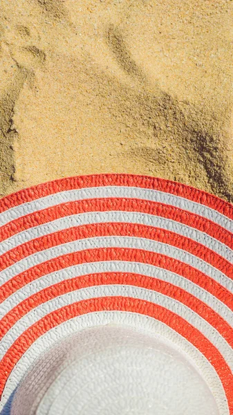 Vista dall'alto della spiaggia sabbiosa con cappello da spiaggia a strisce rosse Sfondo con spazio copia e sabbia visibile FORMATO VERTICALE per Instagram storia mobile o dimensioni storie. Carta da parati mobile — Foto Stock