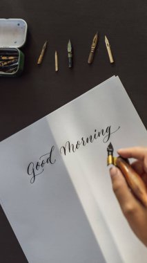 Hattat eller yazar ifade beyaz kağıt üzerinde. İfade - Günaydın. Süs süslü harfler inscribing. Hat sanatı hocası, grafik tasarım, harfler, el yazısı, yaratma kavramı dikey biçimi