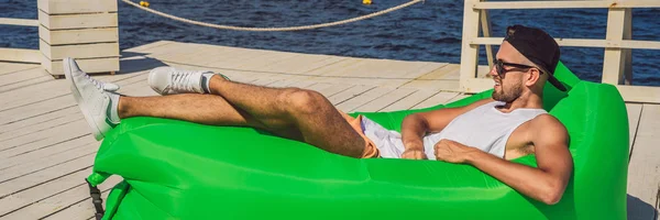 Joven disfrutando del ocio, tumbado en el sofá de aire Lamzac, cerca del mar BANNER, FORMATO LARGO —  Fotos de Stock