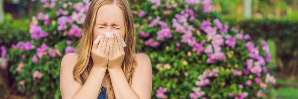 Wanita cantik muda meniup hidung di depan pohon mekar. Konsep alergi musim semi BANNER, LONG FORMAT — Stok Foto