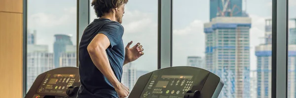 Man running in a gym on a treadmill against the background of a big city. concept for exercising, fitness and healthy lifestyle BANNER, LONG FORMAT — Stock Photo, Image