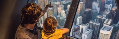 Baba ve oğlu Kuala lumpur cityscape arıyoruz. Gün batımı gökdelenler içinde Malaysia bina panoramik manzaraya Kuala Lumpur şehir manzarası akşam. Çocuklar konseptiyle afiş, uzun biçimde seyahat