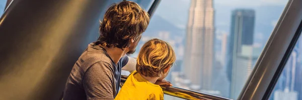 Dad and son are looking at Kuala lumpur cityscape. Panoramic view of Kuala Lumpur city skyline evening at sunset skyscrapers building in Malaysia. Traveling with kids concept BANNER, LONG FORMAT