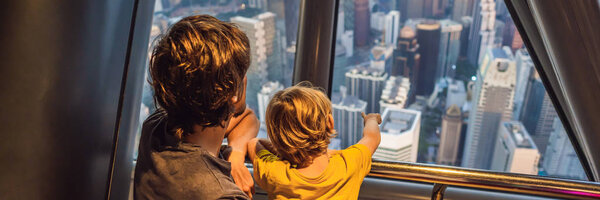 Dad and son are looking at Kuala lumpur cityscape. Panoramic view of Kuala Lumpur city skyline evening at sunset viewing skyscrapers building in Malaysia. Traveling with kids concept. BANNER, LONG