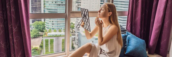 Молодая женщина делает макияж сидя у окна с панорамным видом на небоскребы и большой город Баннер, длинный Формат — стоковое фото