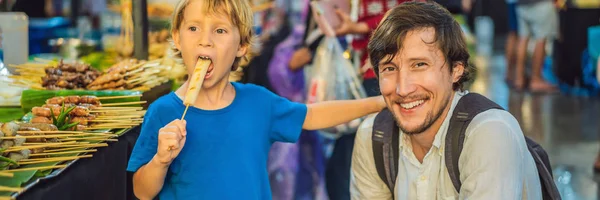 Dad and son are tourists on Walking street Asian food market BANNER, LONG FORMAT