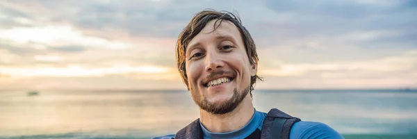 Un uomo prende un selfie sullo sfondo del mare e del tramonto BANNER, FORMATO LUNGO — Foto Stock
