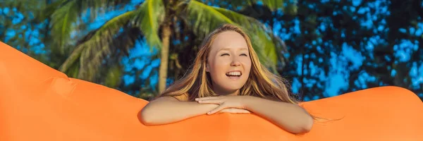 Yaz yaşam tarzı tropik ada plaj turuncu şişme kanepede oturan güzel kız portresi. Rahatlatıcı ve hava yatakta afiş, uzun biçimde hayat zevk — Stok fotoğraf