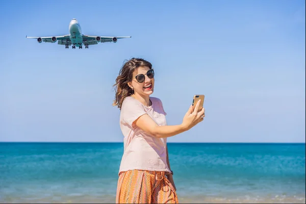 La mujer hace una selfie en la playa viendo los aviones de aterrizaje. Viajando en un concepto de avión. Espacio de texto. Island Phuket en Tailandia. Impresionante paraíso. Playa caliente Mai Khao. Paisaje increíble —  Fotos de Stock