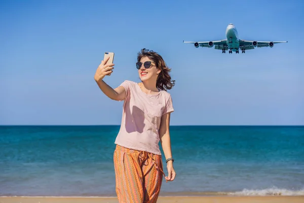 La mujer hace una selfie en la playa viendo los aviones de aterrizaje. Viajando en un concepto de avión. Espacio de texto. Island Phuket en Tailandia. Impresionante paraíso. Playa caliente Mai Khao. Paisaje increíble —  Fotos de Stock