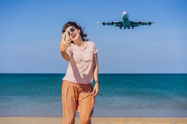 Una donna fa un selfie sulla spiaggia guardando gli aerei di atterraggio. Viaggiare su un concetto di aereo. Spazio di testo. Island Phuket in Thailandia. Un paradiso impressionante. Spiaggia calda Mai Khao. Paesaggio incredibile — Foto Stock